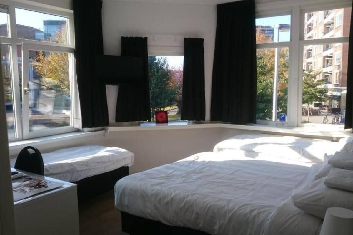 Une chambre avec deux lits, de grandes fenêtres et une vue sur la ville.