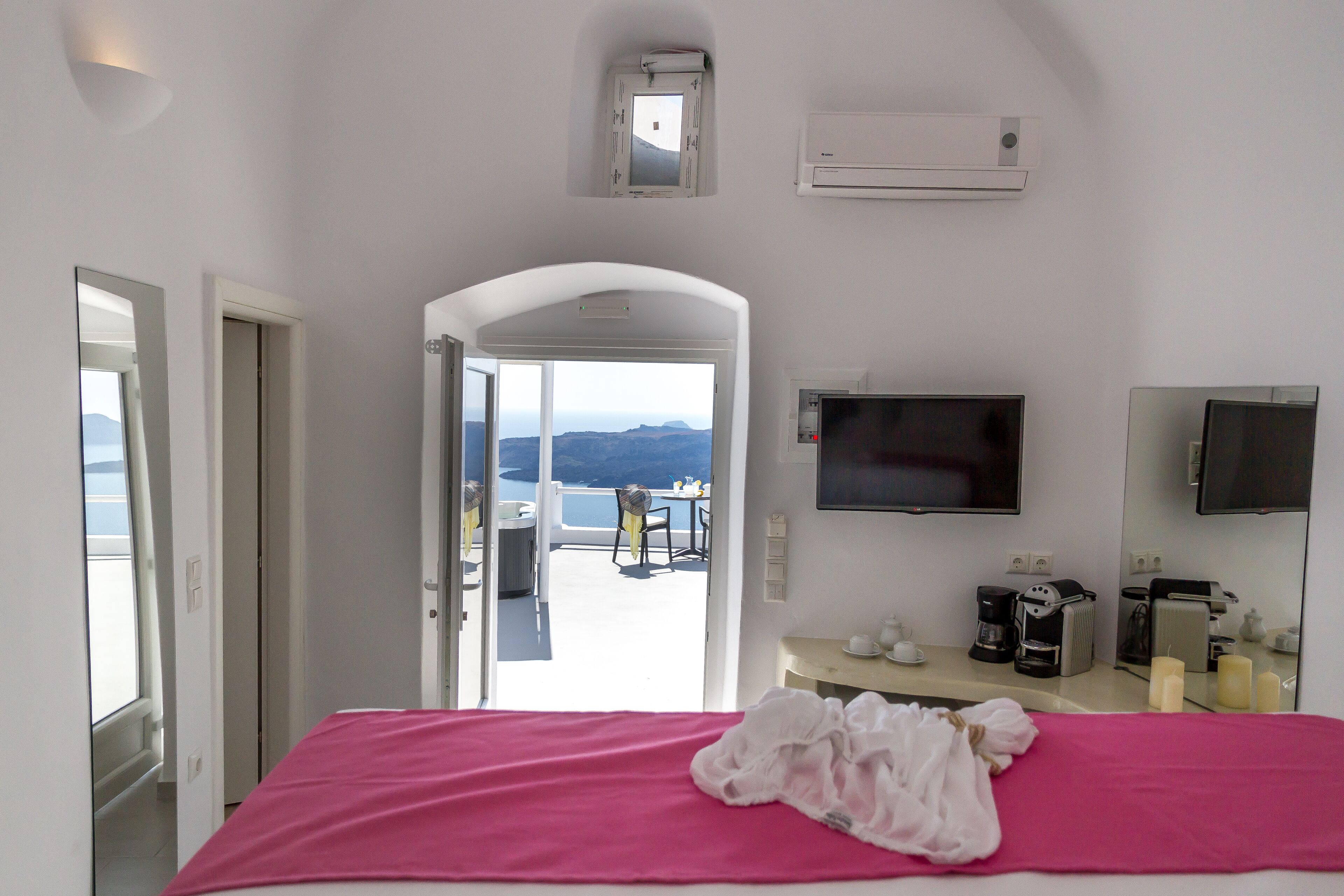 A hotel room with a bed, a TV, a coffee machine, and a view of the mountains.