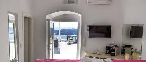 A hotel room with a bed, a TV, a coffee machine, and a view of the mountains.