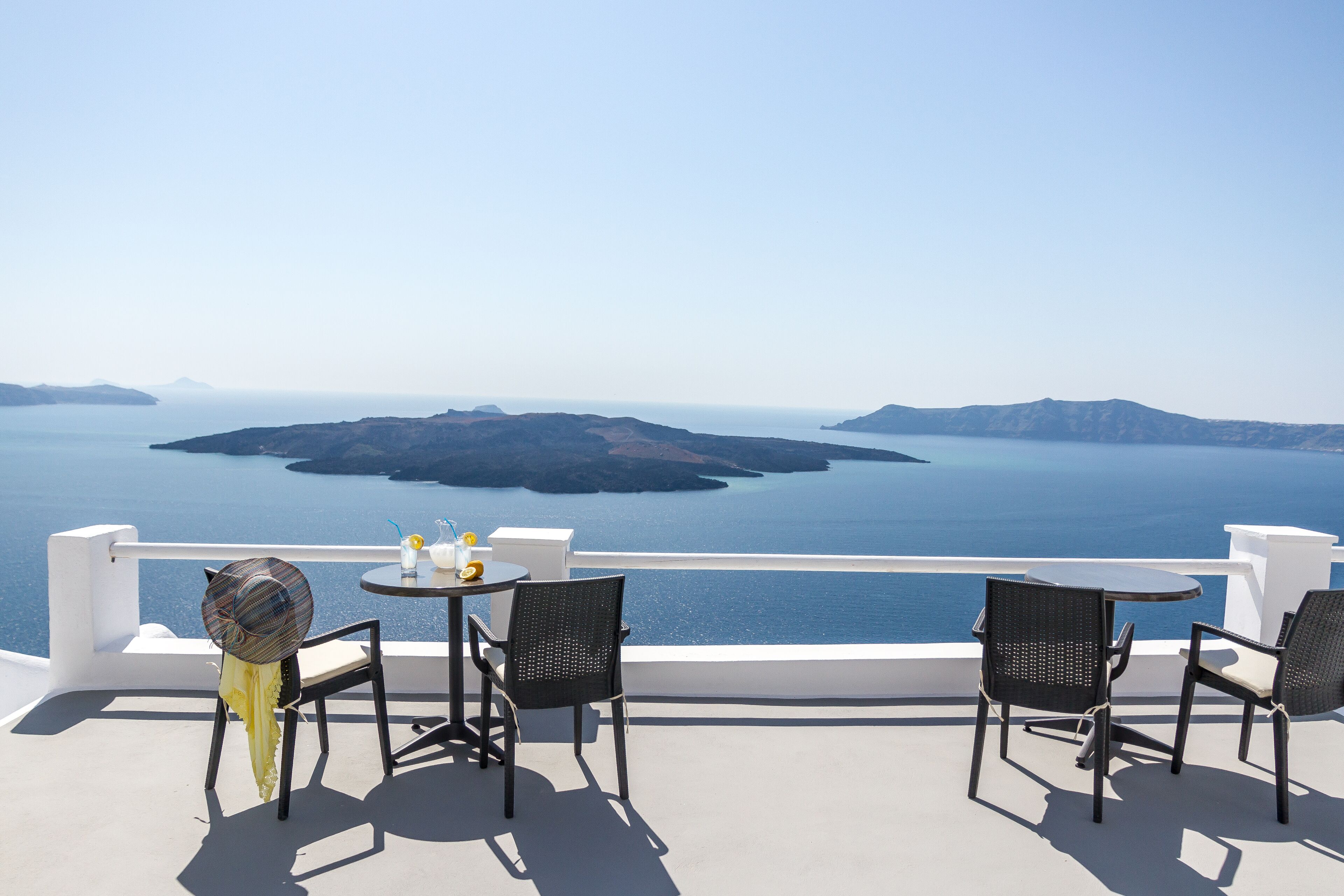 Een terras met twee tafels en stoelen, met uitzicht op een schilderachtige waterpartij en verre landschappen.