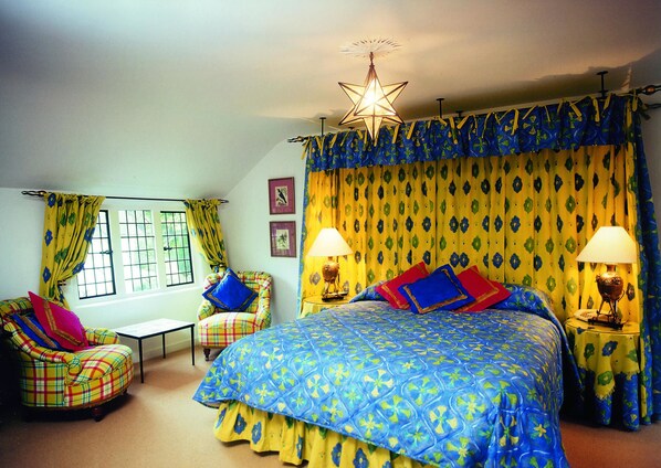 A bedroom with a bed, two chairs, a nightstand, and a star-shaped ceiling light.