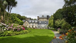 A large stone building with a well-maintained lawn and flower beds.