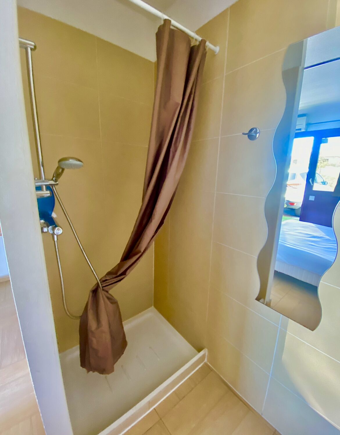 A shower with a curtain, a handheld showerhead, and a wall-mounted faucet.