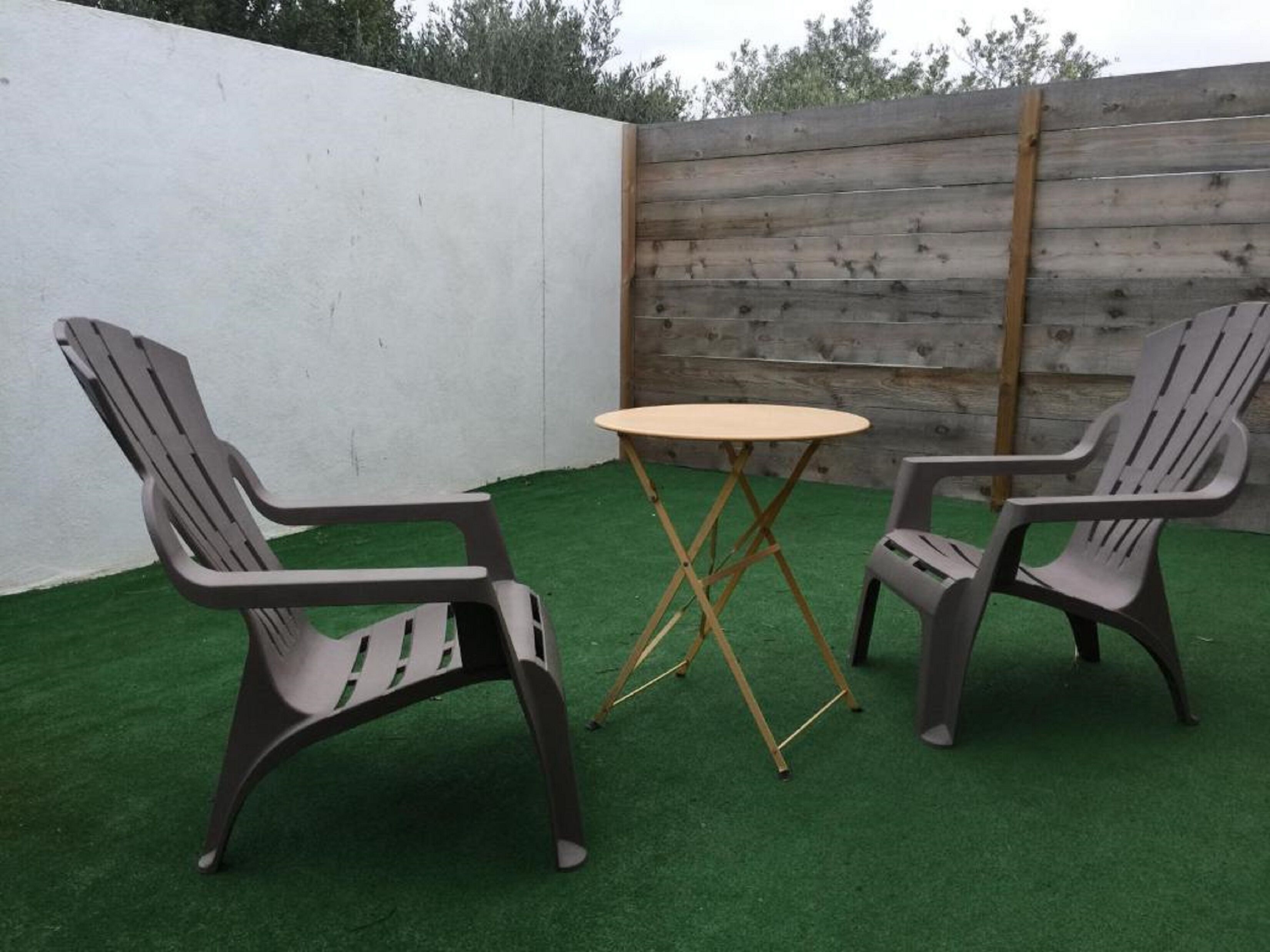 Un área de estar al aire libre con dos sillas Adirondack y una mesa redonda pequeña.