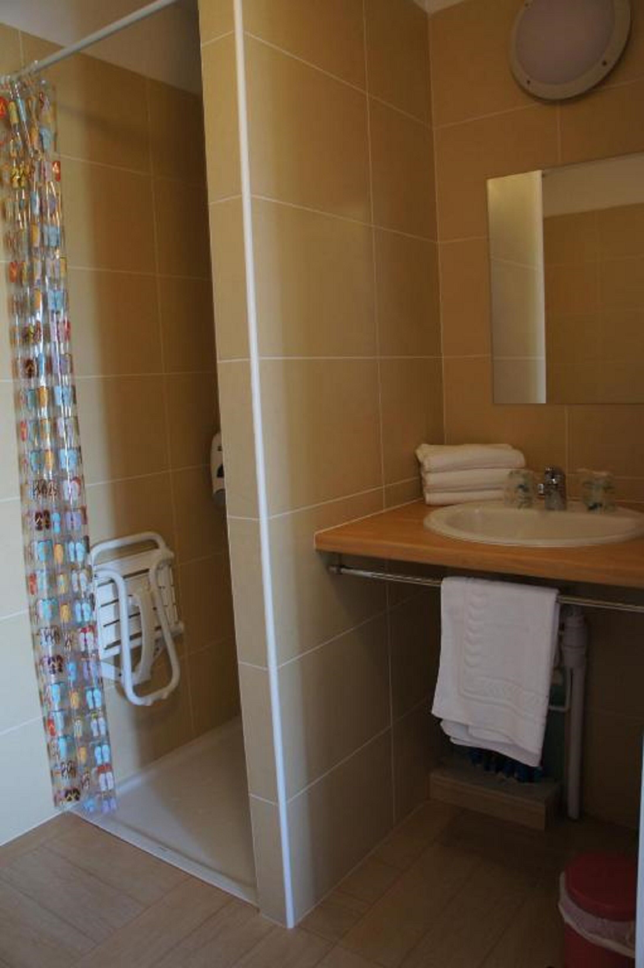 Un baño con ducha, lavabo, espejo y toallero.