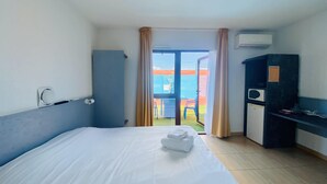 A hotel room with a bed, a desk, a wardrobe, and a view of the outside. - Hôtel Acajou (Argelès-sur-Mer)