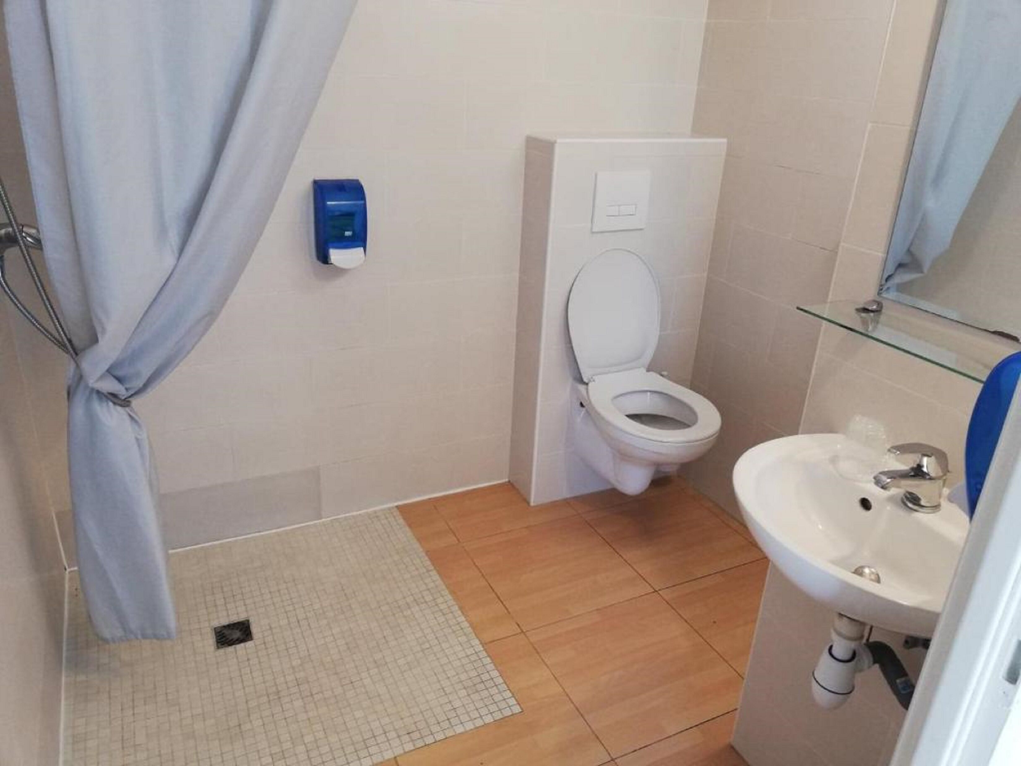 Un baño con inodoro blanco, lavamanos y cortina de ducha.