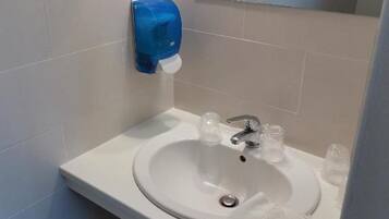Un baño con un lavabo blanco, un espejo y un secamanos azul.