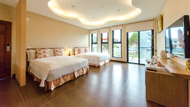 A hotel room with two beds, a TV, and a view of the outdoors. - Ciao House (Hengchun)