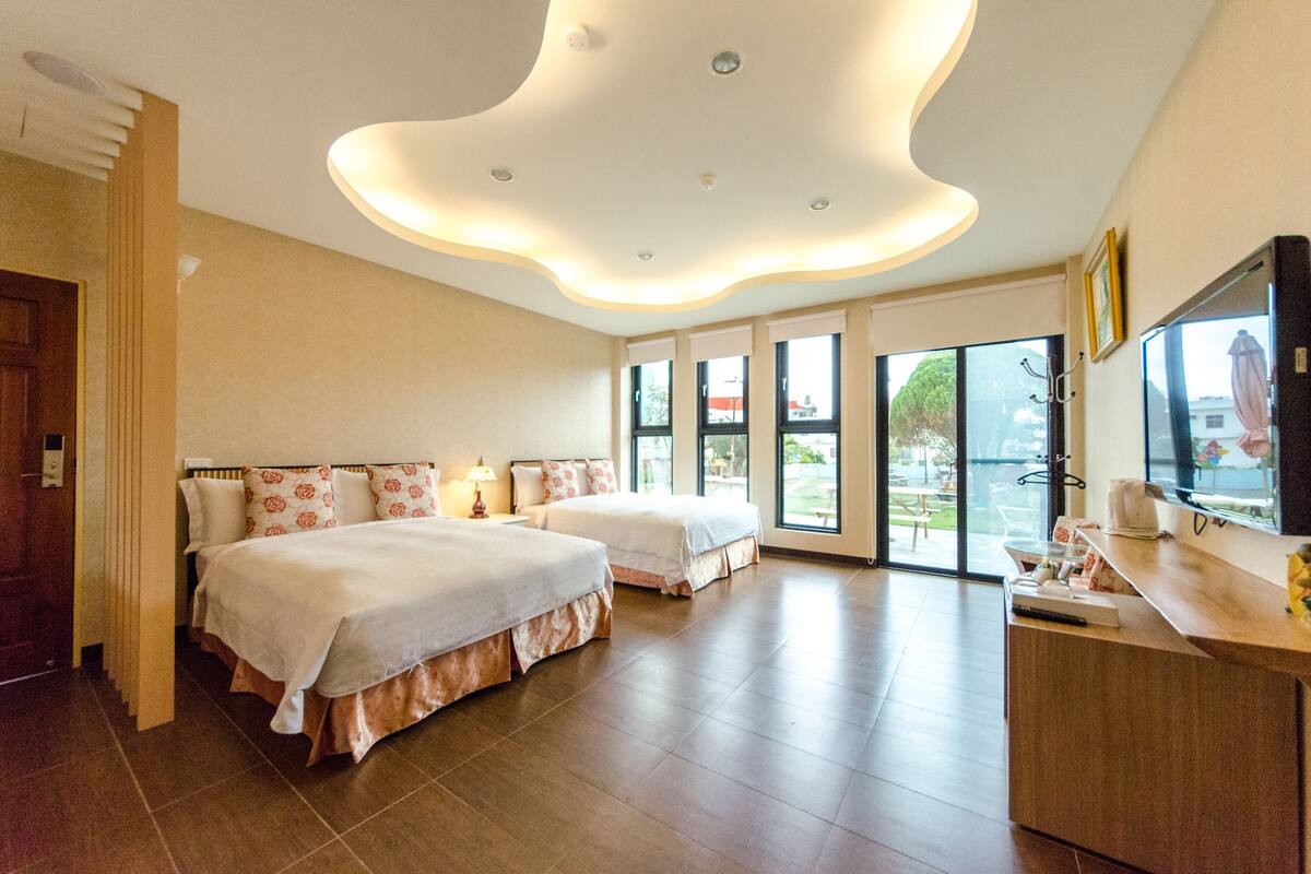 Habitación de hotel con dos camas, televisión y vistas al exterior.