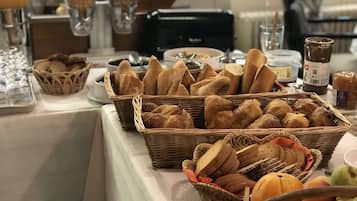 A buffet table with various breads and pastries.