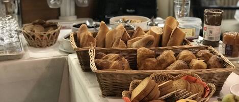 A buffet table with various breads and pastries.
