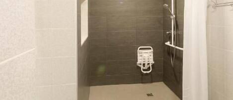 Un baño moderno con ducha, barra de apoyo y perchero.