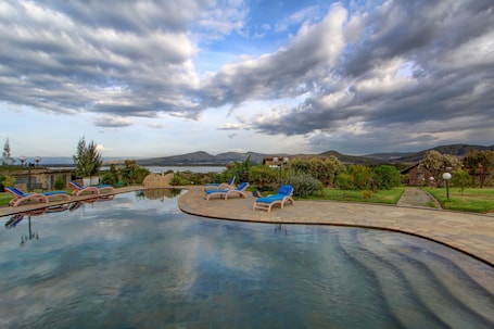 Una piscina al aire libre, sombrillas, sillones reclinables de piscina