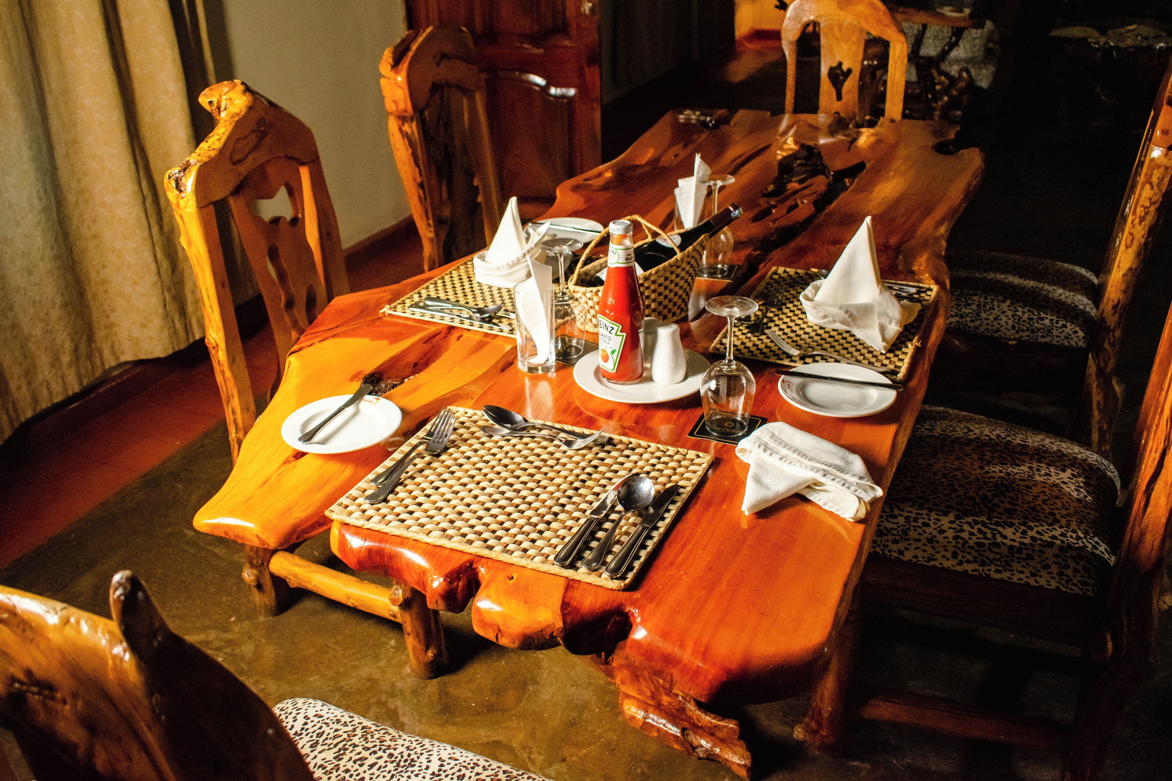 Una mesa de comedor de madera dispuesta con cubiertos, platos y servilletas.
