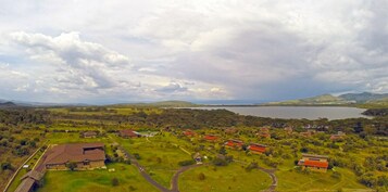 A rural area with a large body of water, green fields, and scattered buildings with red roofs.
