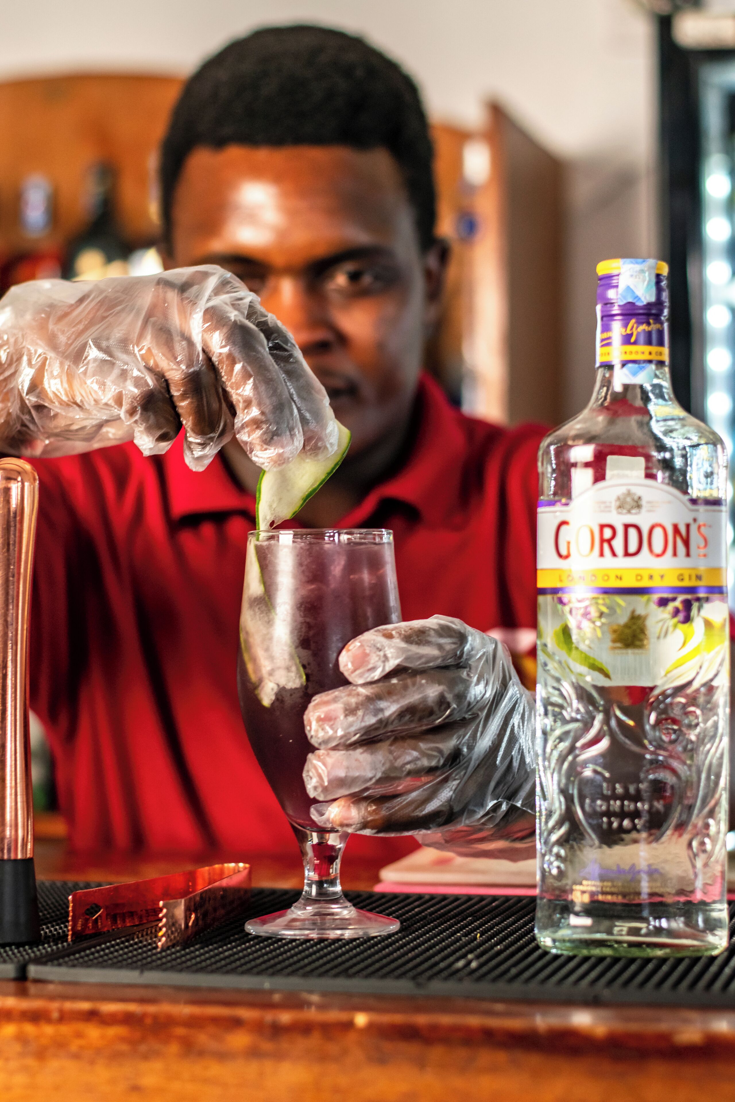 Un barman prépare un cocktail à l’aide d’une bouteille de gin Gordon’s Dry Gin.