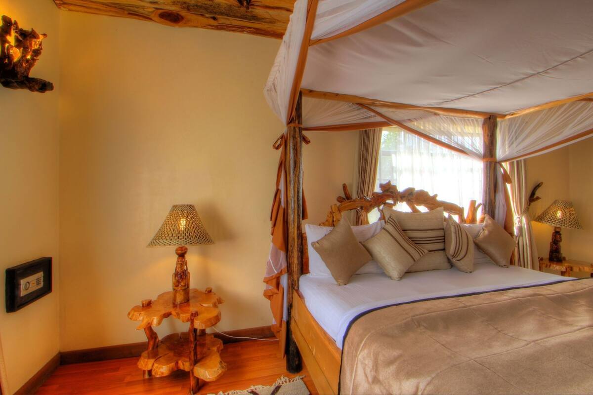 Une chambre dotée d’un lit à baldaquin, de tables de chevet en bois et d’une sculpture en bois unique.