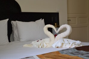 A bed with white linens and a heart-shaped towel arrangement. - Hotel Riad Benatar (Essaouira)