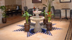 A spacious lobby with a high ceiling, a central fountain, and multiple seating areas. - Hotel Riad Benatar (Essaouira)