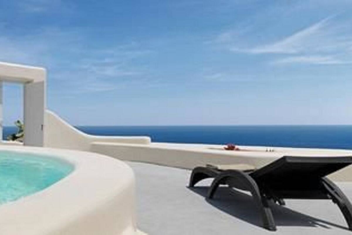 A pool area with a clear view of the ocean, a lounge chair, and a small water feature.