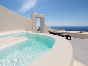 Un jacuzzi con vista despejada al océano, una pared blanca y un acceso.