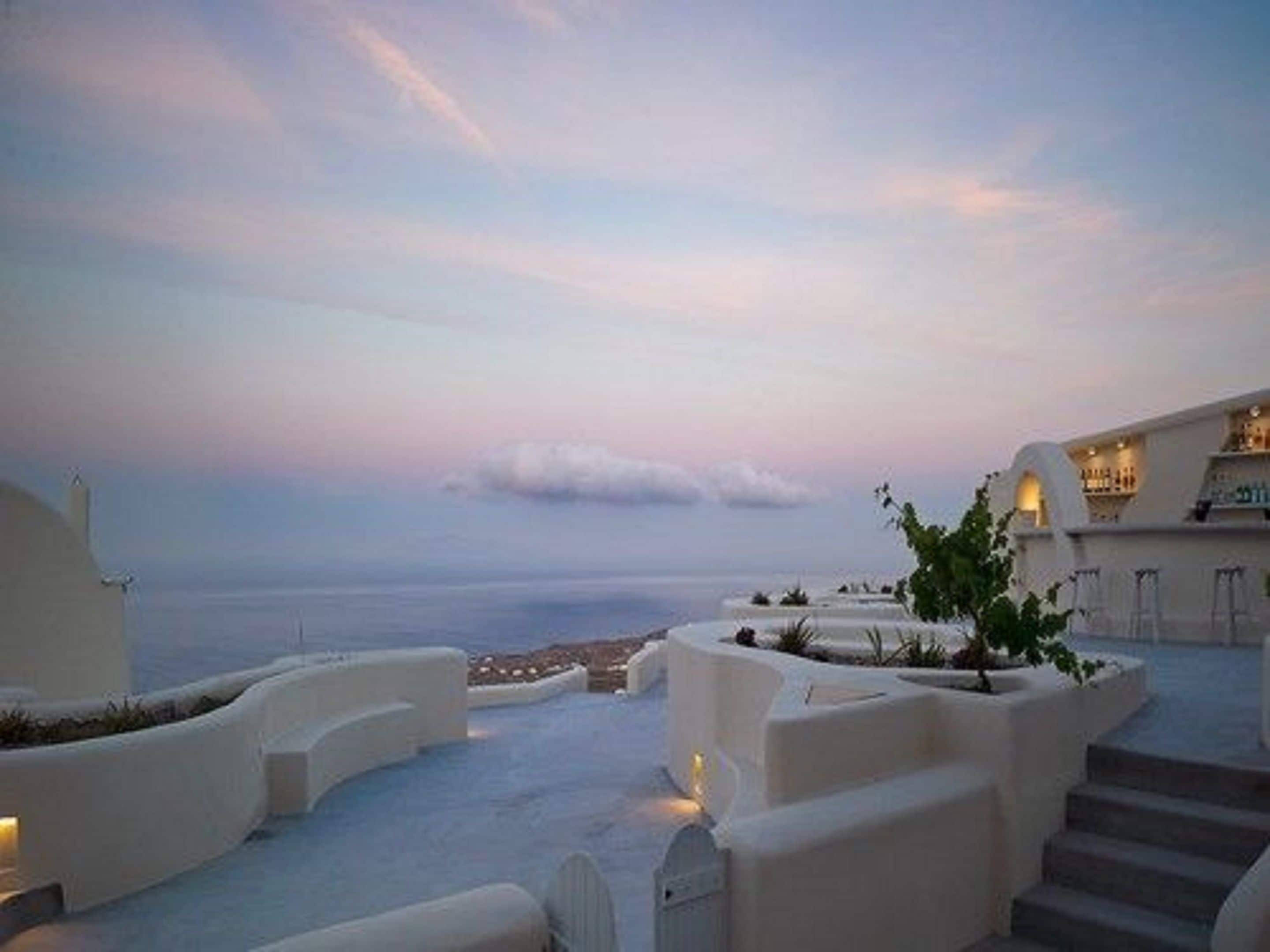 A white building with a curved roof and a view of the sea.
