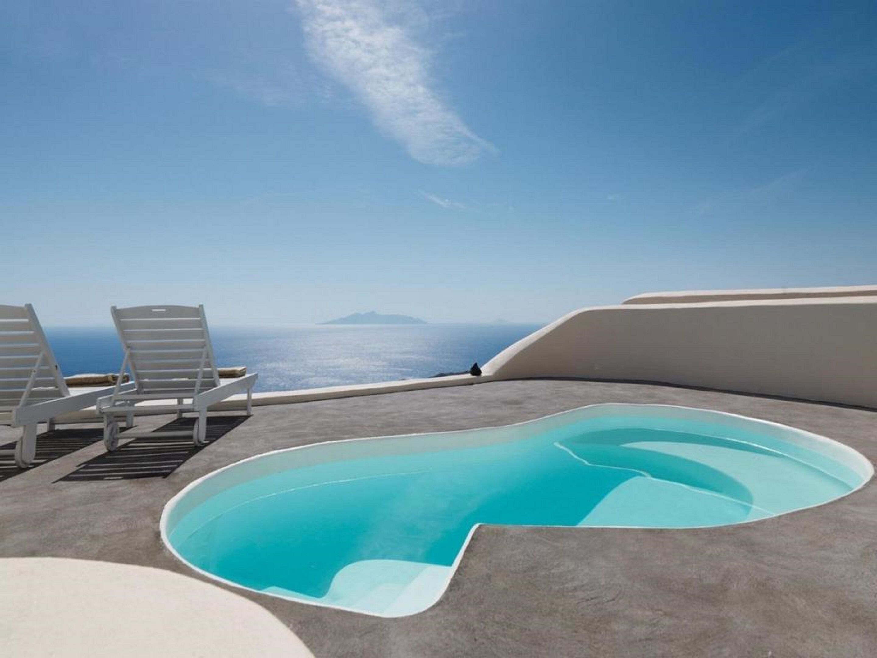 Zona de piscina con sillones de descanso y vista al mar.