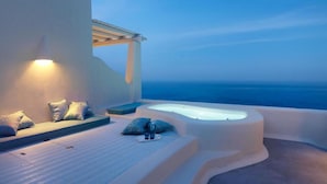 Un moderno espacio lounge al aire libre con un jacuzzi, asientos y vista al océano.