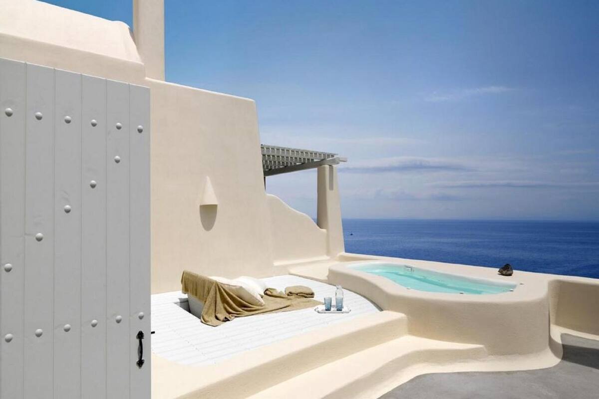 A modern hotel room with a private balcony, a bathtub, and a view of the sea.