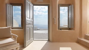 Una habitación con vista al mar, un sofá blanco y una puerta abierta que da al exterior.