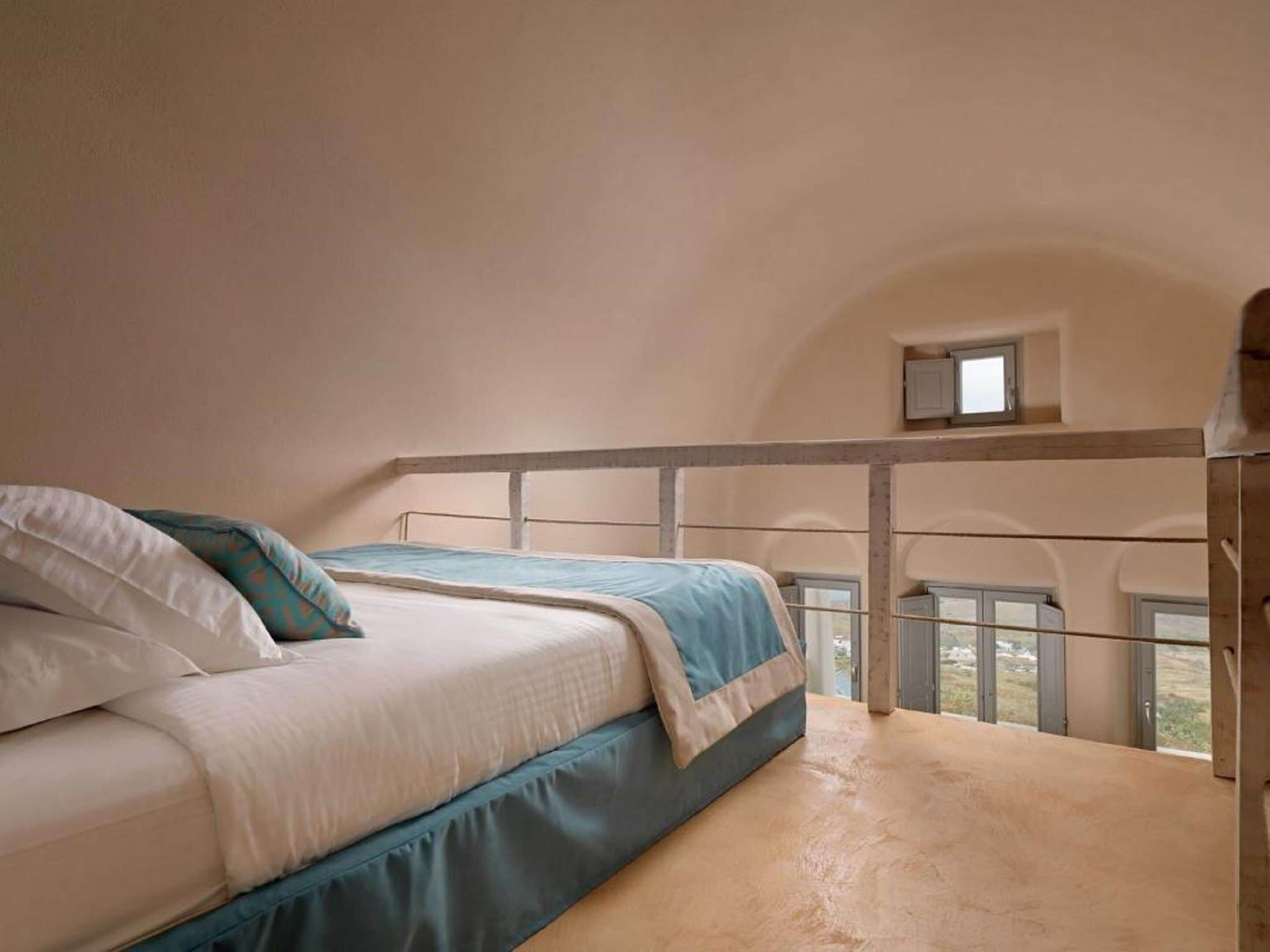 Un dormitorio con cama, una ventana pequeña y un balcón con barandilla.