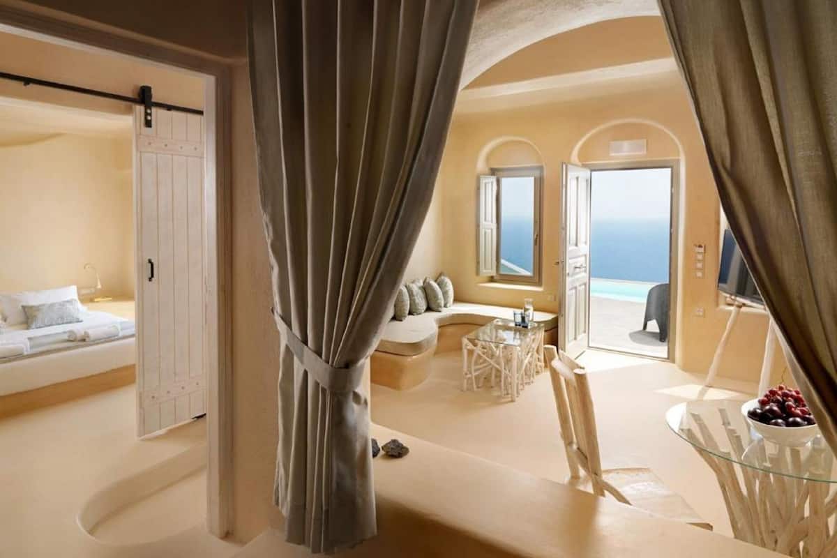 A spacious room with a bed, a seating area, and a view of the ocean.