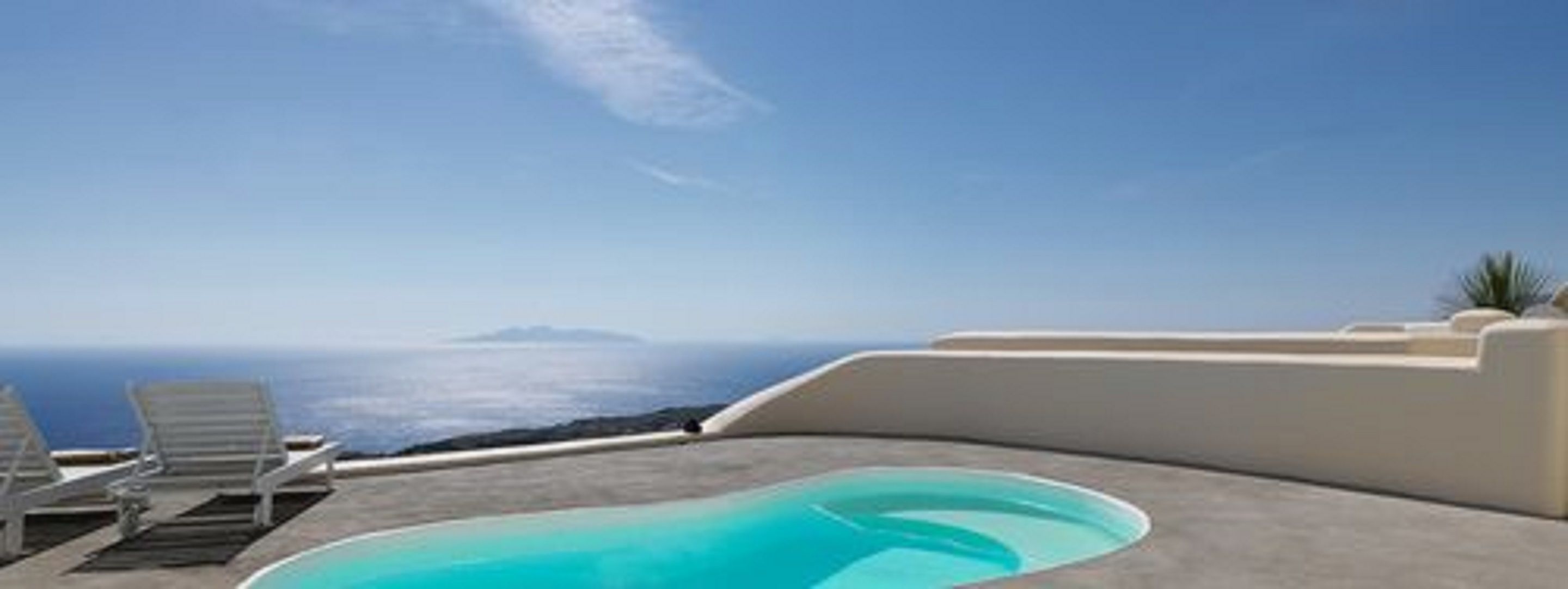 A pool area with lounge chairs and a view of the ocean.