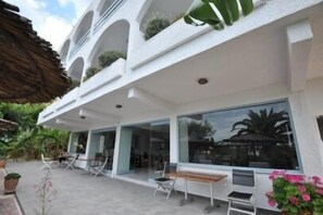 Un edificio moderno con varios balcones, ventanas amplias y mobiliario exterior.
