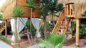 Una estructura con techo de paja y una escalera de madera que lleva a una plataforma.