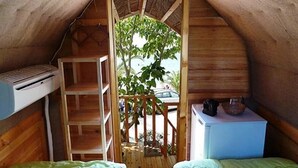 Un pequeño dormitorio en el ático con una escalera de madera, un escritorio pequeño y una cama.