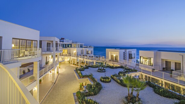 Een modern hotel met meerdere balkons met uitzicht op een strand.