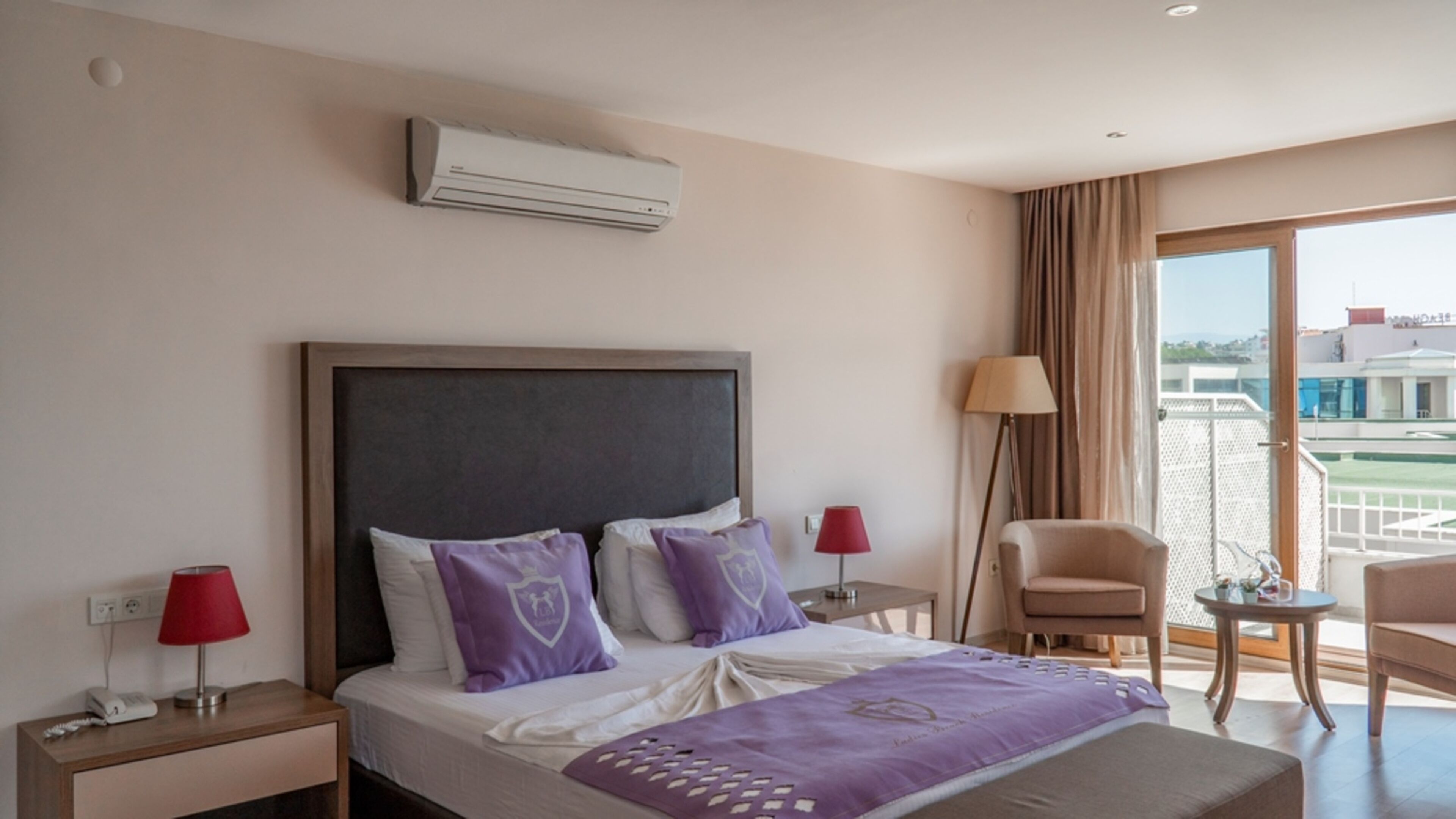 Habitación de hotel con cama, una silla, una mesa, aire acondicionado y vistas al exterior.