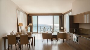 Een moderne hotelkamer met een zithoek, een keuken en een groot raam met uitzicht op zee.