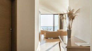 Een moderne kamer met uitzicht op zee, een bank, een eettafel en een vaas met gedroogde planten.