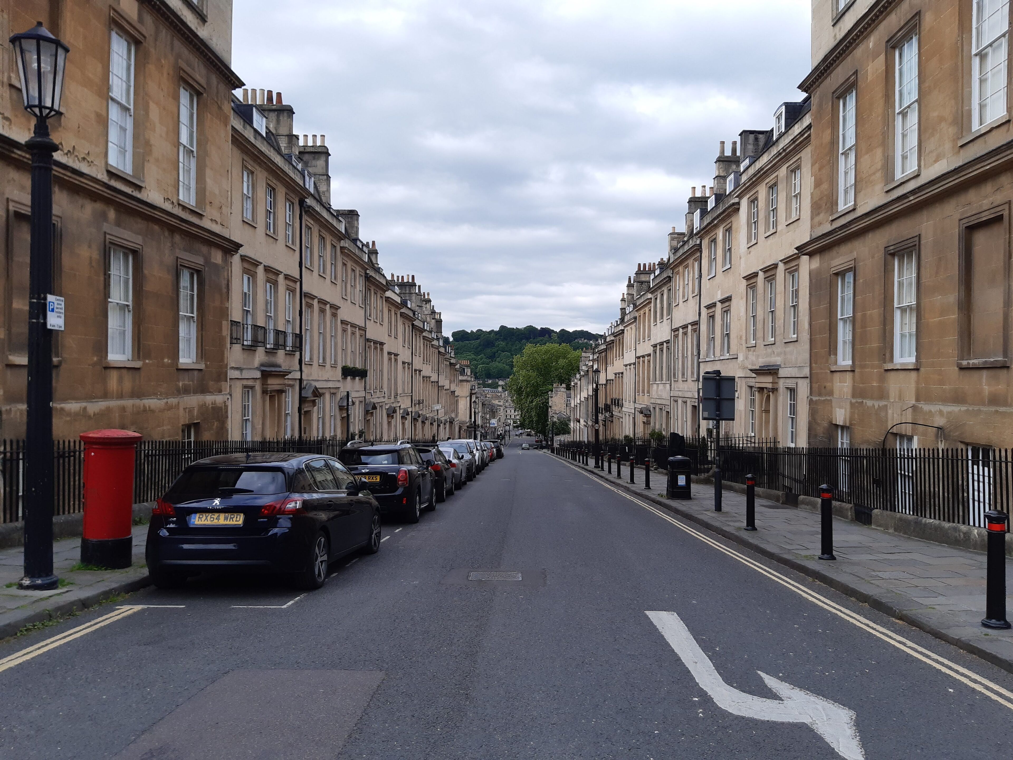 A street lined with historic buildings, parked cars, and a clear road.