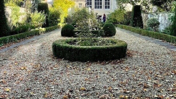 A multi-story building with a central courtyard featuring a circular garden and a pathway. - Brocks Guest House (Bath)