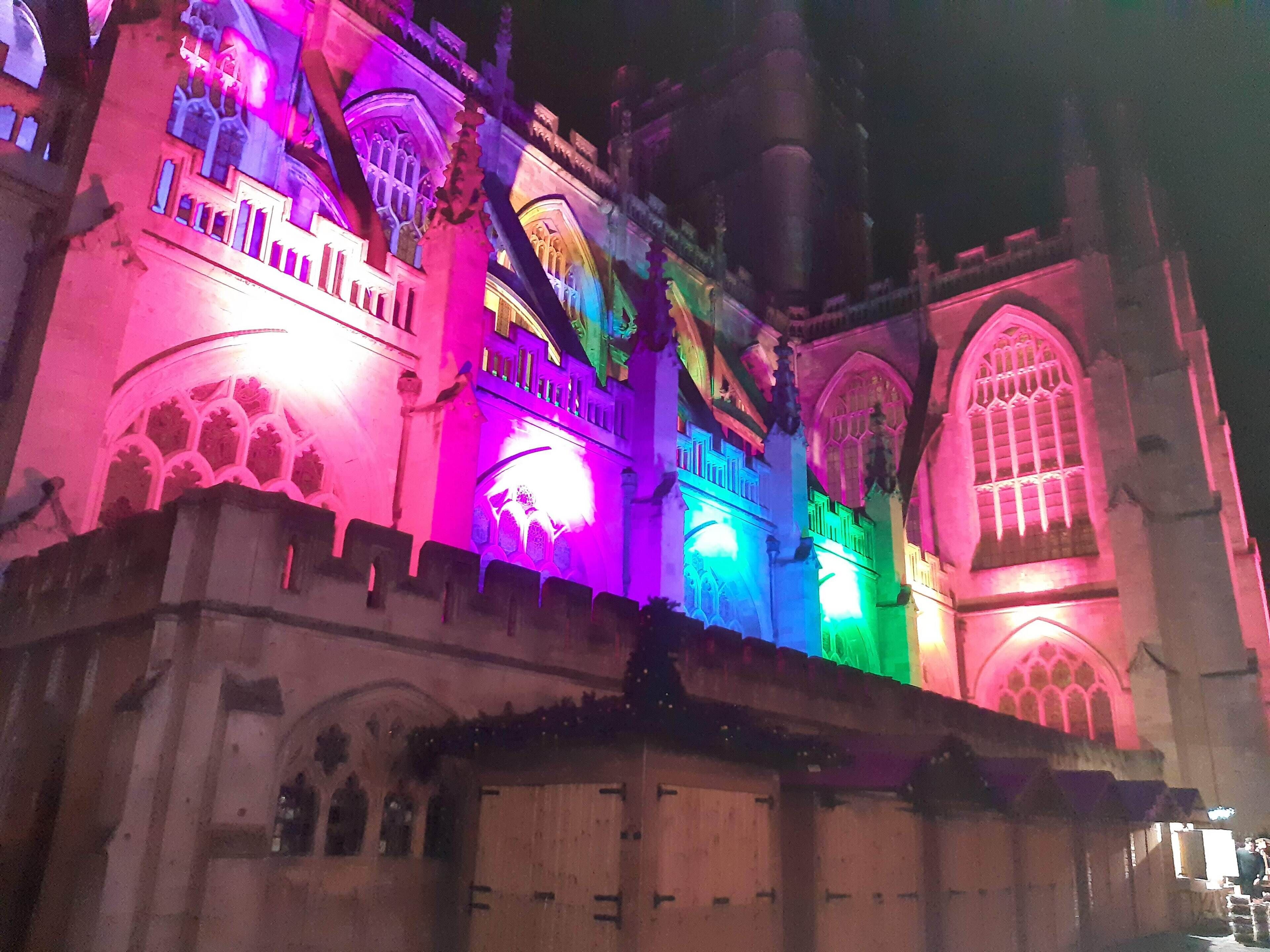 A historic building with Gothic architecture, illuminated with colorful lights.