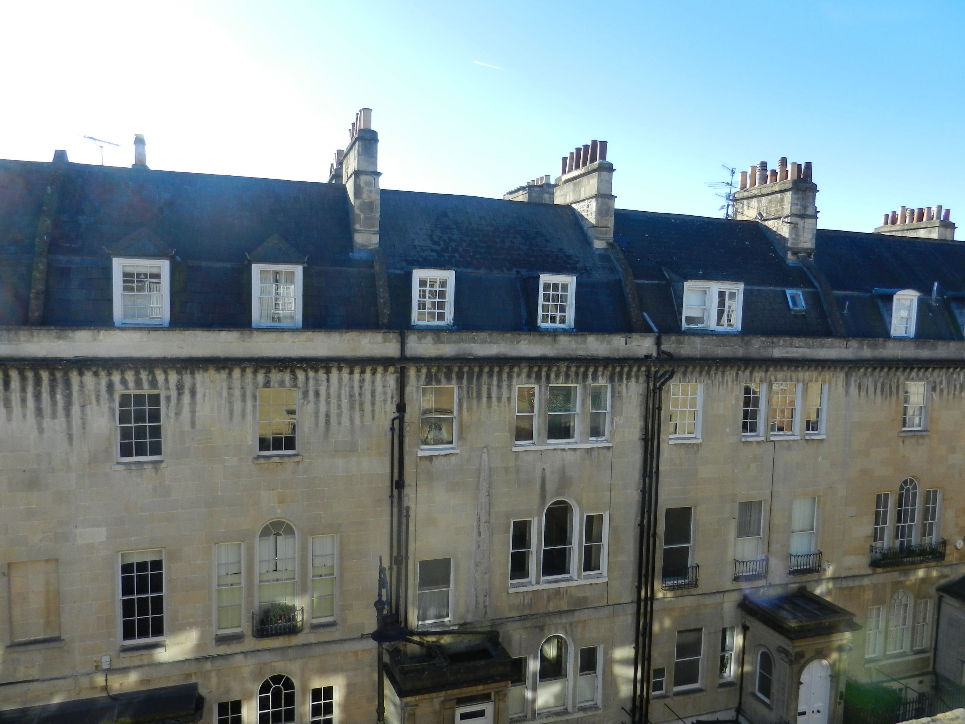 A multi-story building with a row of windows on the upper floor and a balcony on the lower floor.