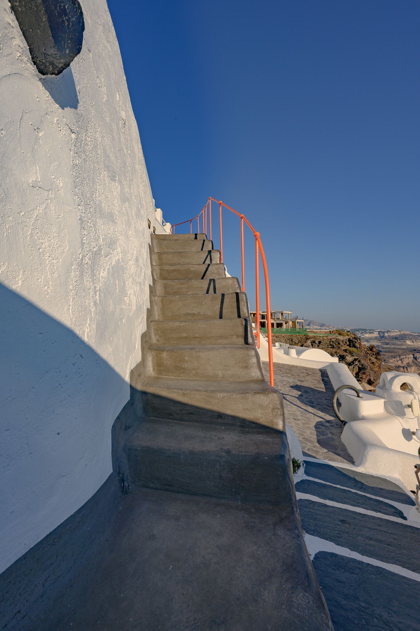 A concrete staircase with orange railings leading to a building with a white exterior.