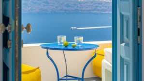 A room with a view of the sea, a table with a glass and a lime, and a blue door.