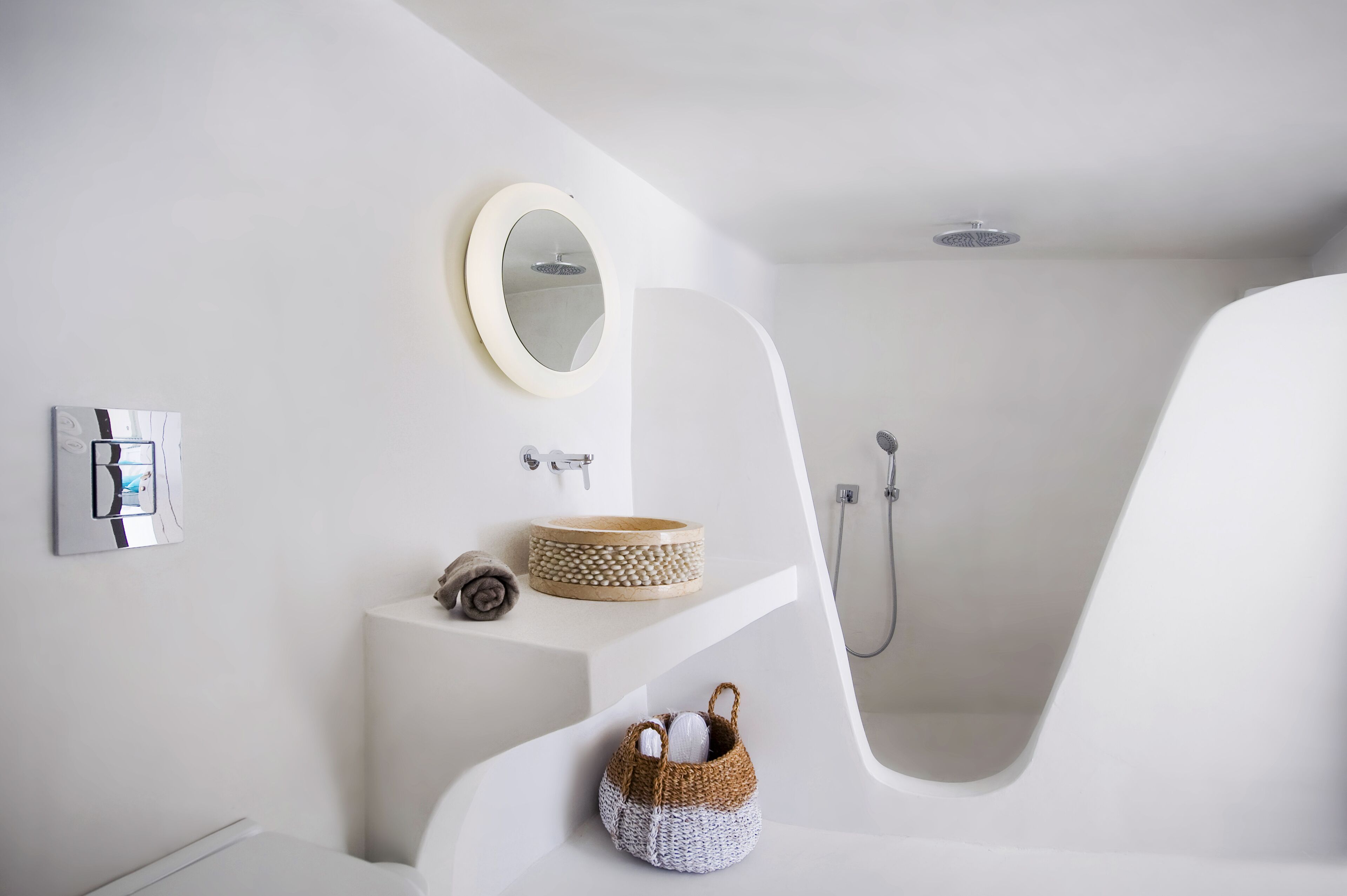 Un baño moderno con un lavamanos blanco, un espejo redondo, una ducha y una bañera.