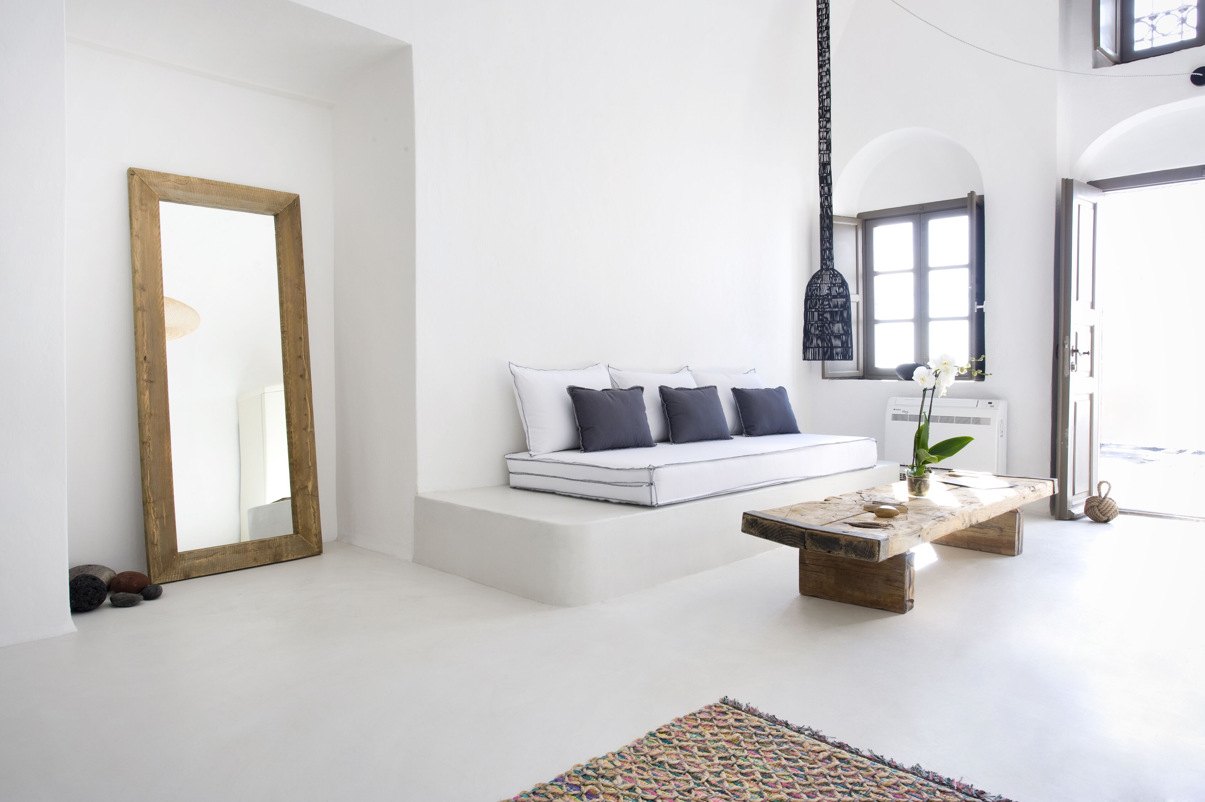 Un salon minimaliste avec un canapé blanc, une table basse en bois et un grand miroir.