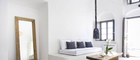 Un salon minimaliste avec un canapé blanc, une table basse en bois et un grand miroir.